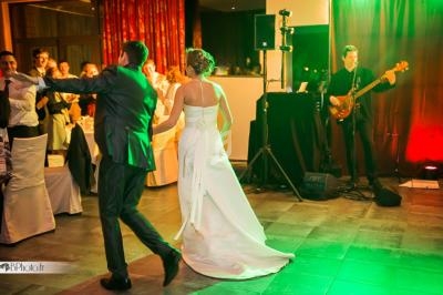 Un couple danse lors d'une réception, accompagné d'un musicien jouant de la basse en arrière-plan.