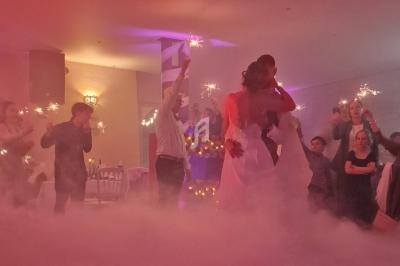 Des invités dansent avec des cierges magiques dans une salle éclairée par des lumières tamisées et un effet de fumée au sol.