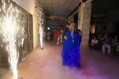 Un couple danse au centre d'une salle décorée, entouré de fumée et d'effets lumineux.