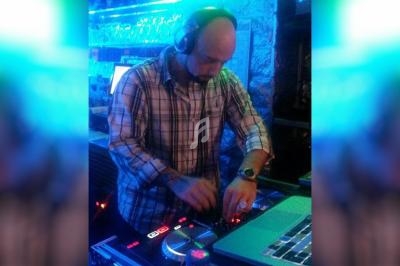 Un DJ mixe de la musique sur une console dans un environnement éclairé par des lumières bleues.