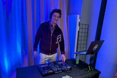 Un DJ mixe de la musique sur une table de mixage dans une pièce éclairée par des lumières bleues.