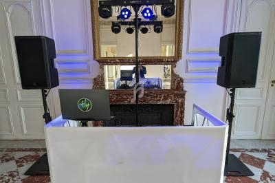 Console de DJ avec éclairage et enceintes installée dans une salle élégante avec cheminée et miroir.