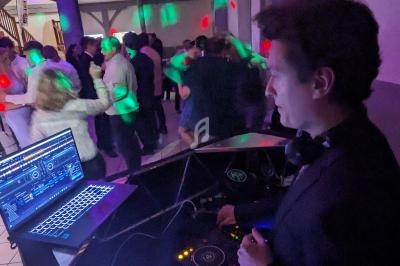 Un DJ mixe de la musique sur une console, face à une piste de danse animée avec des lumières colorées.