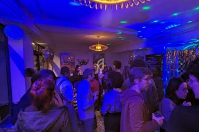 Groupe de personnes discutant dans une salle éclairée par des lumières colorées, ambiance festive.