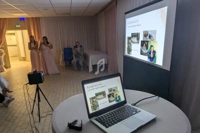 Un ordinateur portable et un projecteur affichent une présentation dans une salle décorée, avec des invités en arrière-plan.