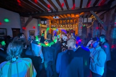 Groupe de personnes dansant dans une salle éclairée par des lumières colorées et des guirlandes lumineuses.