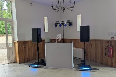 Installation de matériel de sonorisation et d'éclairage dans une salle avec murs blancs et fenêtres étroites.