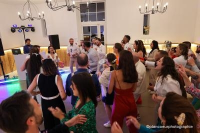 Groupe de personnes dansant et célébrant dans une salle éclairée avec des chandeliers et un DJ en arrière-plan.