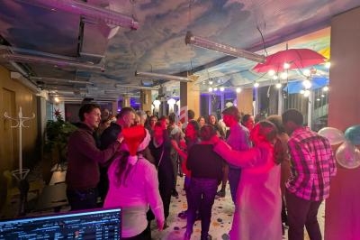 Groupe de personnes discutant et partageant un moment convivial dans une salle décorée avec des lumières et des parapluies…