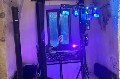 Équipement de sonorisation et éclairage installé dans une pièce voûtée avec un mur en pierre et une fenêtre centrale.