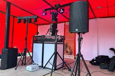 Équipement de sonorisation et éclairage installé sous une tente rouge pour un événement ou une performance musicale.