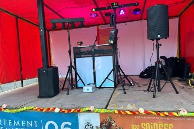 Scène sous un chapiteau rouge avec équipement de sonorisation et éclairage pour un événement musical.