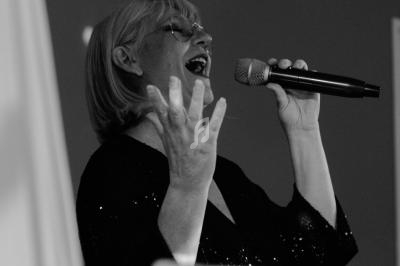 Femme chantant avec un micro à la main, exprimant une émotion intense dans un environnement sombre.