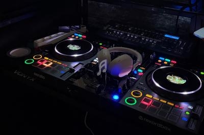 Console de mixage DJ éclairée avec casque audio posé au centre, entourée de boutons et platines lumineuses.