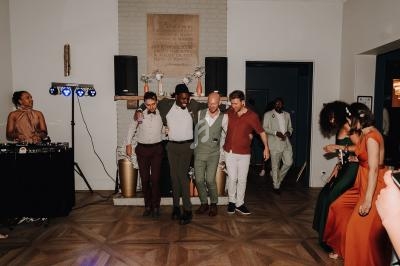 Un groupe de personnes dansant et souriant lors d'une fête dans une salle avec un parquet en bois.