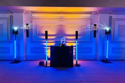 Installation lumineuse avec projecteurs et colonnes LED diffusant des couleurs bleues et jaunes dans une salle.