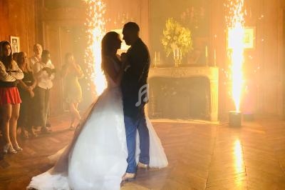 Un couple danse au centre d'une salle élégante avec des étincelles lumineuses en arrière-plan.