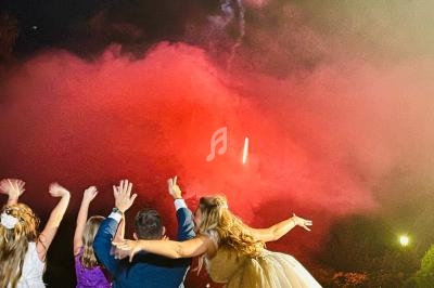 Groupe de personnes regardant un feu d'artifice illuminant le ciel nocturne de fumée rouge.