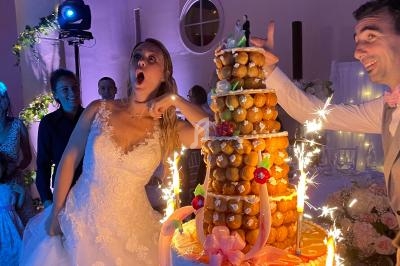 Une mariée surprise et un marié coupant une pièce montée éclairée de bougies étincelantes lors d'une réception.