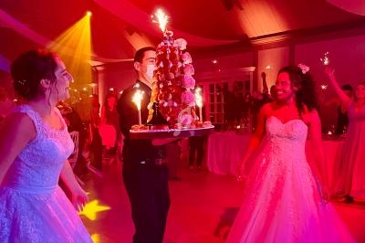Un serveur apporte une pièce montée décorée de bougies étincelantes lors d'une fête avec des invités en tenue de soirée.