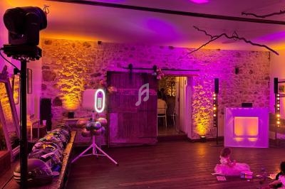 Salle décorée pour un événement avec éclairage coloré, ballons et jeux pour enfants au sol.