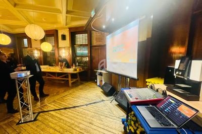 Salle de réception avec projecteur, table de buffet éclairée et équipement audio sur un sol en bois.