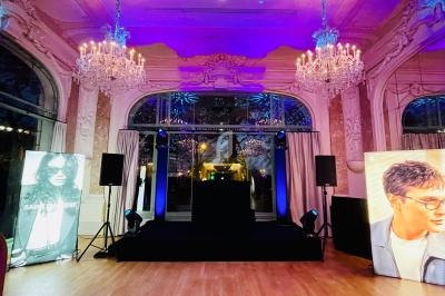 Salle élégante avec lustres, scène centrale, affiches publicitaires et éclairage coloré.