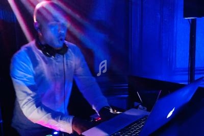 Un DJ mixant de la musique sur un ordinateur portable dans une ambiance lumineuse bleutée.