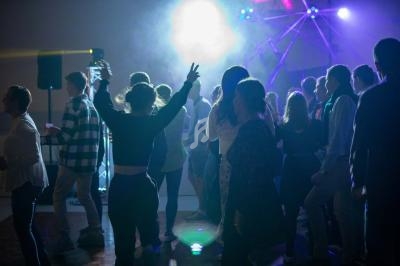 Groupe de personnes dansant sous des lumières colorées dans une ambiance festive.