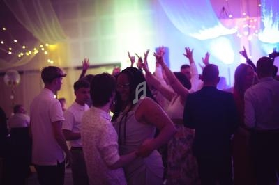 Personnes dansant et discutant dans une salle éclairée par des lumières colorées, ambiance festive.