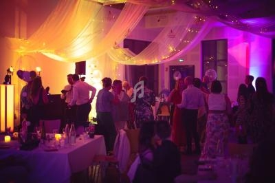 Groupe de personnes dans une salle décorée de voilages et lumières, lors d'un événement festif en soirée.