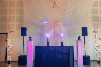 Installation de matériel de sonorisation et éclairage avec jeux de lumière violets dans une salle au plafond décoré.