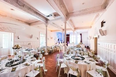 Salle de réception élégante avec tables rondes dressées, décorations florales et éclairage chaleureux.