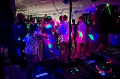 Personnes dansant sous des lumières colorées dans une ambiance festive avec une table de mixage au premier plan.