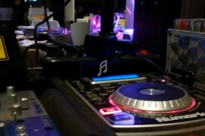 Platines de DJ avec éclairage coloré en arrière-plan dans un environnement de soirée ou d'événement.