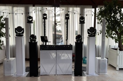 Installation de matériel d'éclairage et de sonorisation dans une salle lumineuse avec rideaux blancs et plantes décoratives.