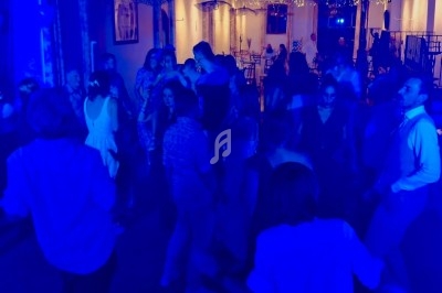 Groupe de personnes dansant dans un espace éclairé par des lumières bleues et guirlandes lumineuses.