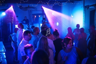 Personnes dansant dans une salle éclairée par des lumières colorées et des projecteurs lors d'une fête.