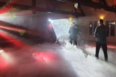 Un couple danse au milieu d'une piste enveloppée de fumée, éclairée par des lumières colorées et des lasers.