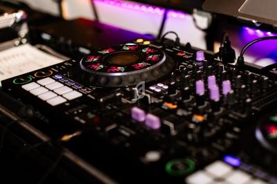 Table de mixage DJ avec boutons, curseurs et éclairages colorés dans un environnement sombre.