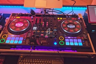 Table de mixage DJ avec platines, boutons lumineux et écran tactile, installée sur un bureau éclairé.