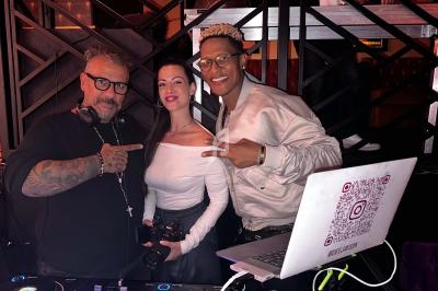 Trois personnes souriantes posent devant un équipement de DJ dans un environnement intérieur avec éclairage tamisé.