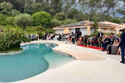 Un photographe capture une réception en plein air près d'une piscine, entourée d'invités et de végétation.