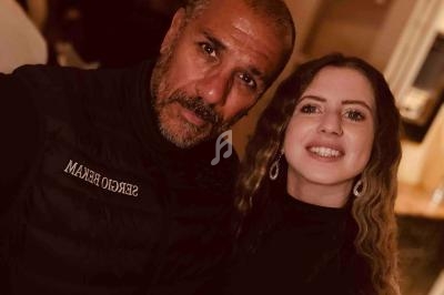 Un homme et une femme sourient face à l'objectif dans un environnement intérieur faiblement éclairé.