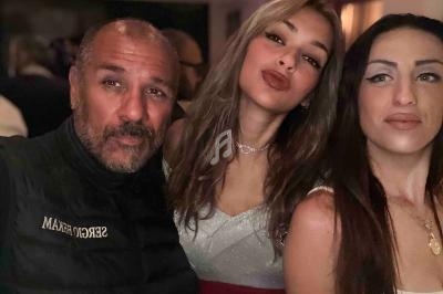 Un homme et deux femmes posent ensemble dans un environnement intérieur faiblement éclairé.