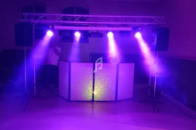 Installation de matériel de sonorisation et d'éclairage avec projecteurs violets dans une salle sombre.