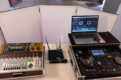 Équipement de DJ comprenant une table de mixage, un ordinateur portable, un micro et des platines dans un espace intérieur.