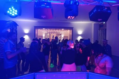 Groupe de personnes dans une salle éclairée par des lumières colorées, participant à une soirée festive.