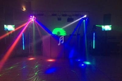 Jeu de lumières colorées projetées dans une salle sombre avec des écrans et un équipement de sonorisation.