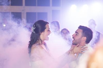 Une femme et un homme dansent au milieu de la fumée, entourés d'autres personnes dans une ambiance festive.